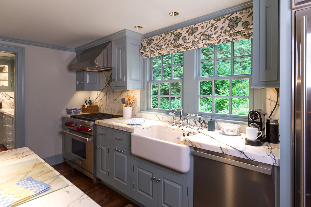 Painted cabinets around the kitchen sink and window frame.